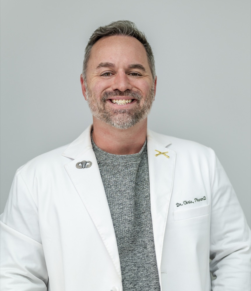 Dr. Chris, a Doctor of Pharmacy, in a white coat embroidered with his name.
